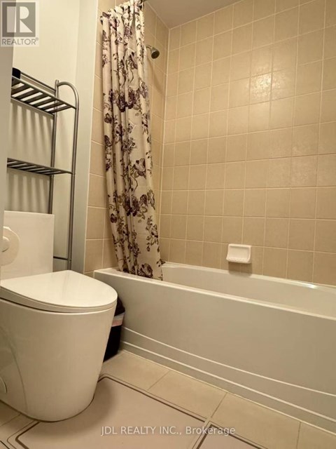 A white toilet sits next to a bathtub in a bathroom.