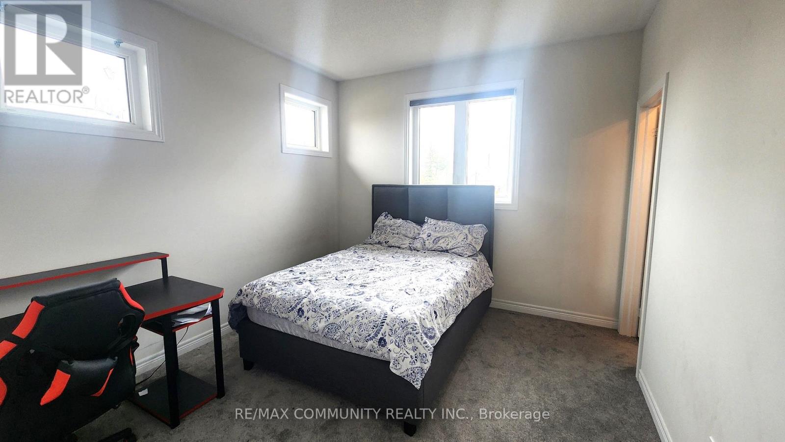 A bedroom with a bed, chair, and window.