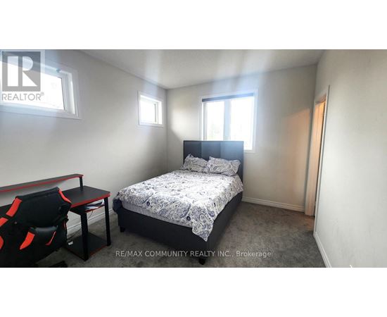 A bedroom with a bed, chair, and window.