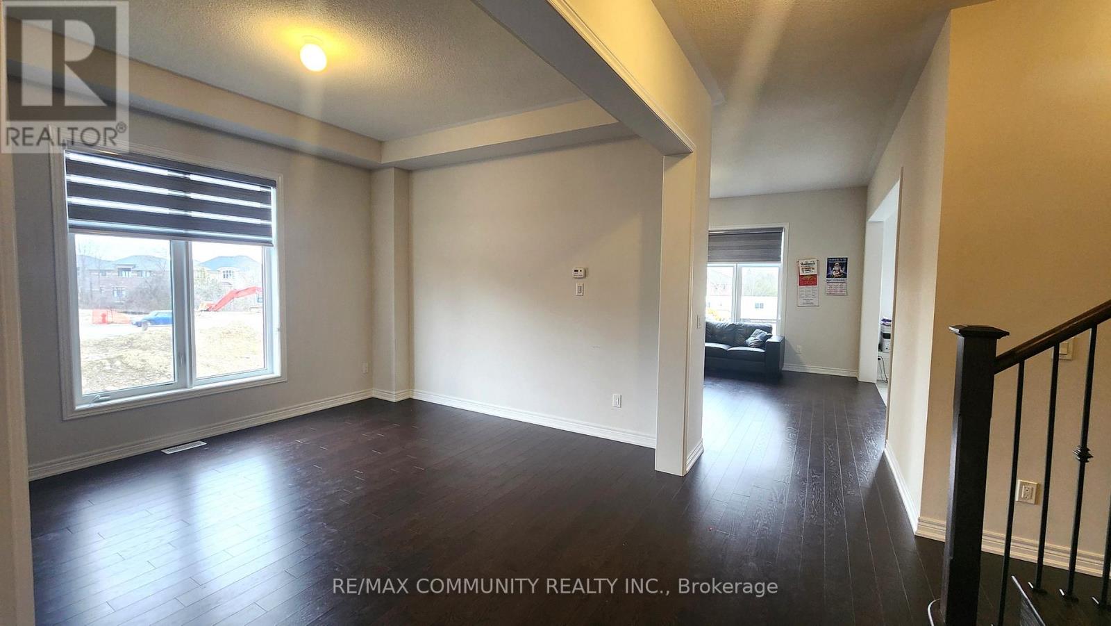 A spacious room with wooden floors and a large window with blinds.