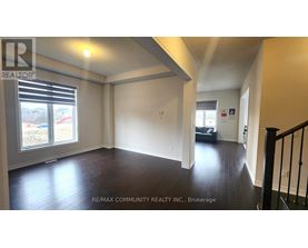 A spacious room with wooden floors and a large window with blinds.
