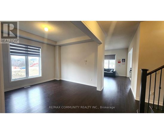 A spacious room with wooden floors and a large window with blinds.