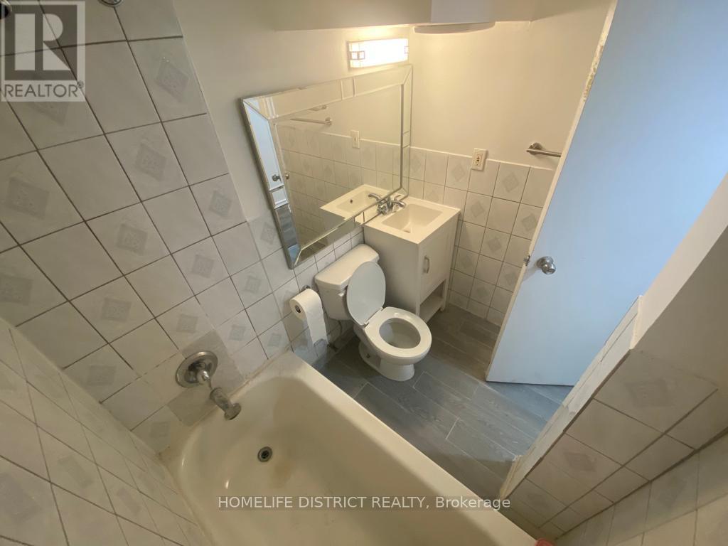 A bathroom with a toilet, sink, and mirror.