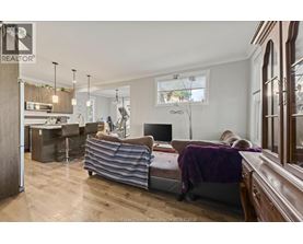 A well-lit, spacious bedroom with a large bed and a kitchen area in the background.