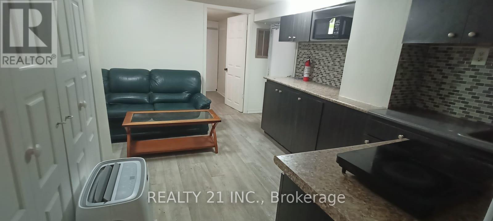 A black leather sofa sits in a kitchen with a wooden coffee table in front of it.