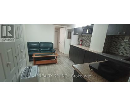 A black leather sofa sits in a kitchen with a wooden coffee table in front of it.