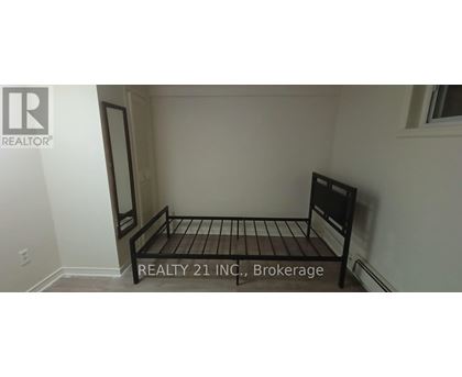 A bedroom with a bed and a sign that says "REALTY 21 INC, Brokerage".