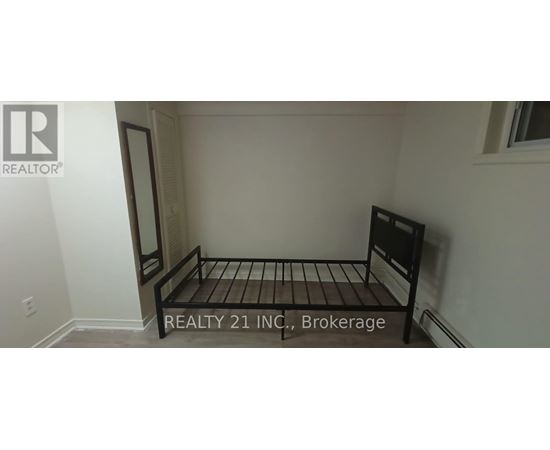 A bedroom with a bed and a sign that says "REALTY 21 INC, Brokerage".