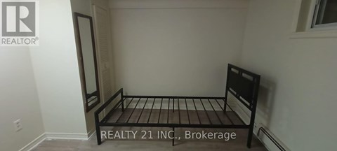 A bedroom with a bed and a sign that says "REALTY 21 INC, Brokerage".