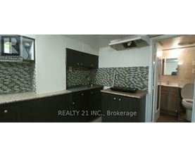 A bathroom with a black counter top and a mirror above it.