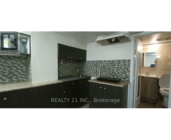 A bathroom with a black counter top and a mirror above it.