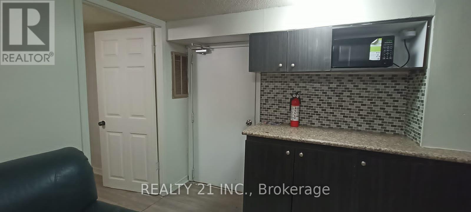 A small kitchen with a black counter top and a white door.