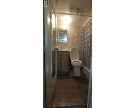A bathroom with a toilet, sink, and mirror.