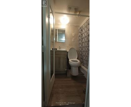 A bathroom with a toilet, sink, and mirror.