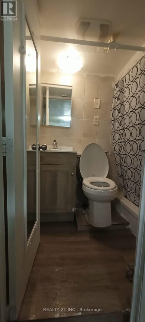 A bathroom with a toilet, sink, and mirror.