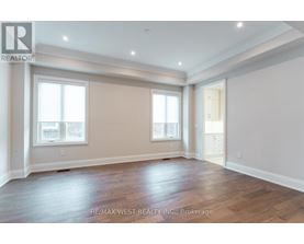 A spacious room with wooden flooring and two windows.