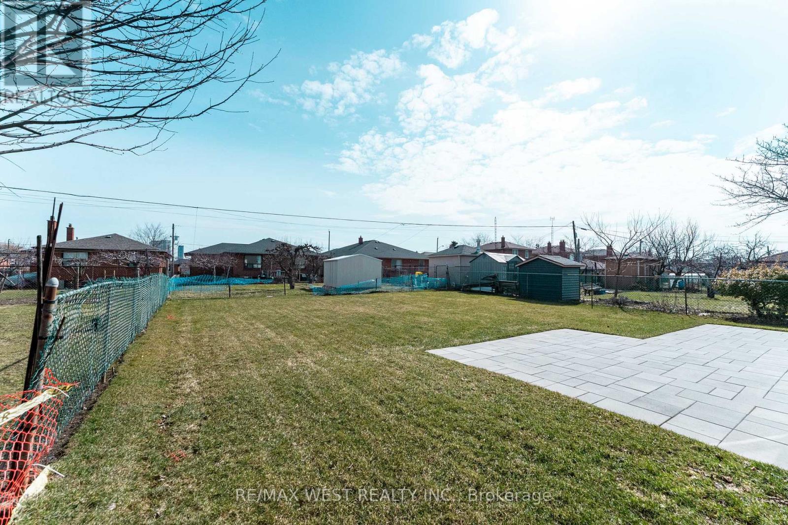 A large grassy area with a fence and a building in the background.