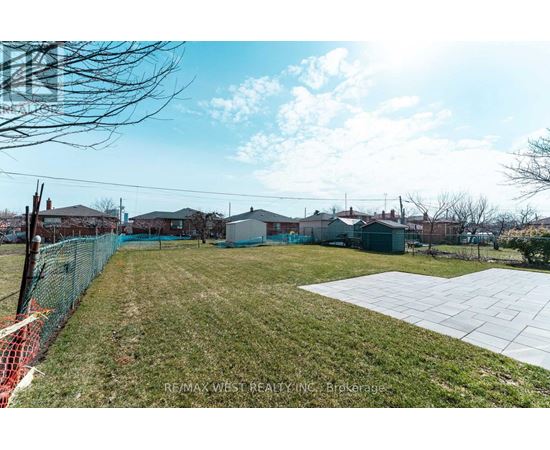 A large grassy area with a fence and a building in the background.