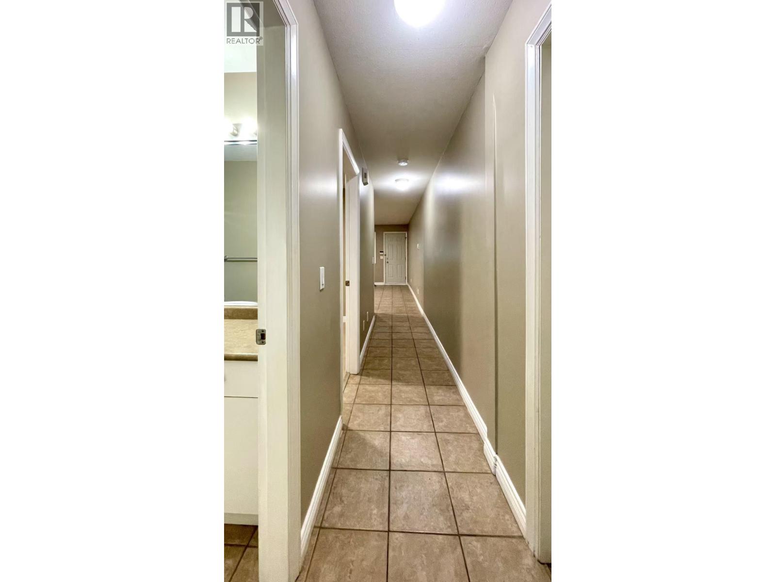 A long hallway with tiled floors and white walls.