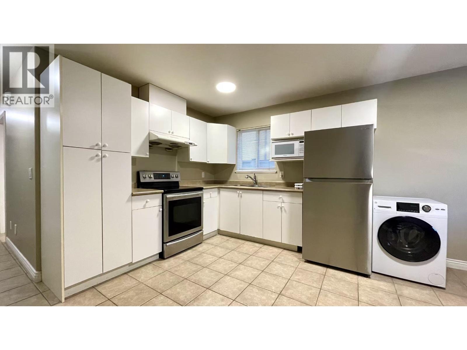 A clean, white kitchen with a washer and dryer built in.