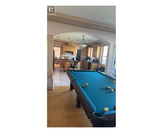 A pool table in a room with a high ceiling and a bar area.