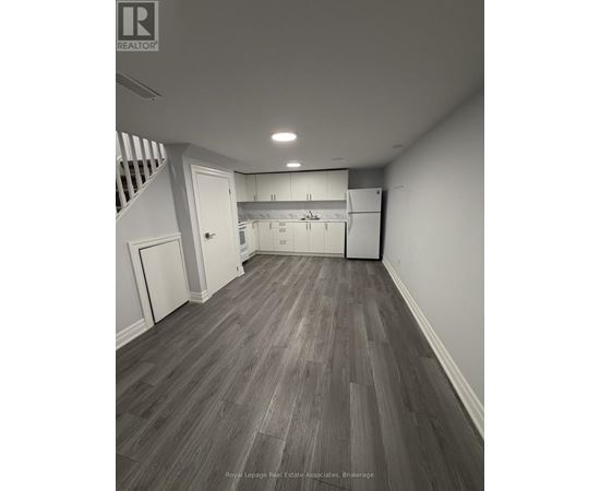 A spacious room with wooden flooring and white walls.