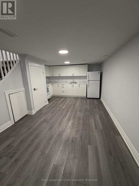 A spacious room with wooden flooring and white walls.