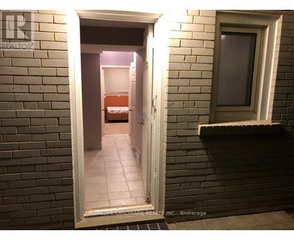 A bedroom is visible through a doorway in a brick wall.