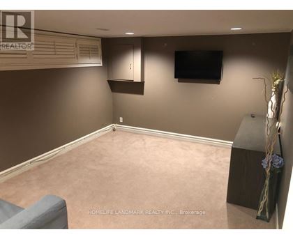 A living room with a grey couch and a flat screen TV mounted on the wall.