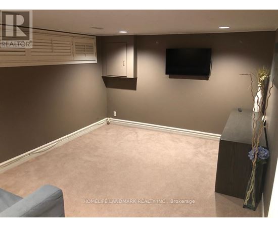 A living room with a grey couch and a flat screen TV mounted on the wall.