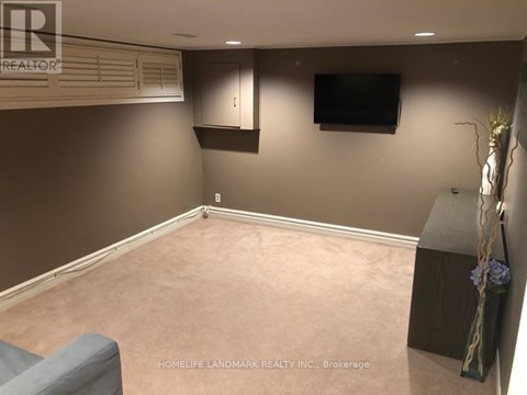 A living room with a grey couch and a flat screen TV mounted on the wall.