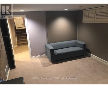 A living room with a grey couch and a staircase in the background.