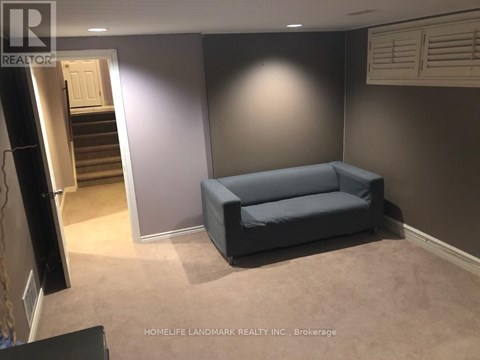 A living room with a grey couch and a staircase in the background.