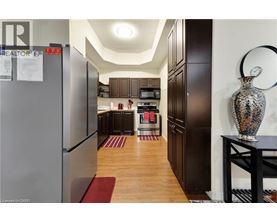 A kitchen with a refrigerator on the left and a table with a vase on it on the right.