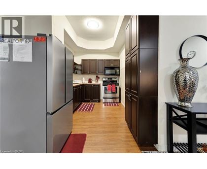 A kitchen with a refrigerator on the left and a table with a vase on it on the right.