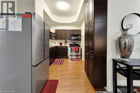 A kitchen with a refrigerator on the left and a table with a vase on it on the right.