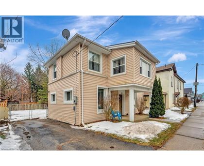 A two-story house with a beige siding and a satellite dish on the roof.