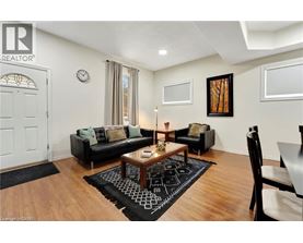 A living room with a black couch, a coffee table, and a rug with a black and white pattern.