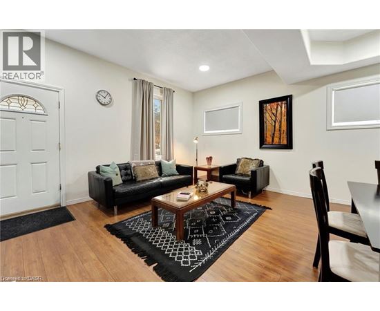 A living room with a black couch, a coffee table, and a rug with a black and white pattern.