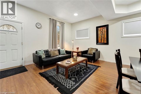 A living room with a black couch, a coffee table, and a rug with a black and white pattern.