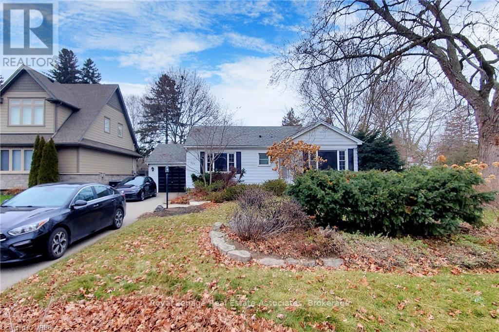 A realtor logo is superimposed on a photo of a house with a car parked in front.