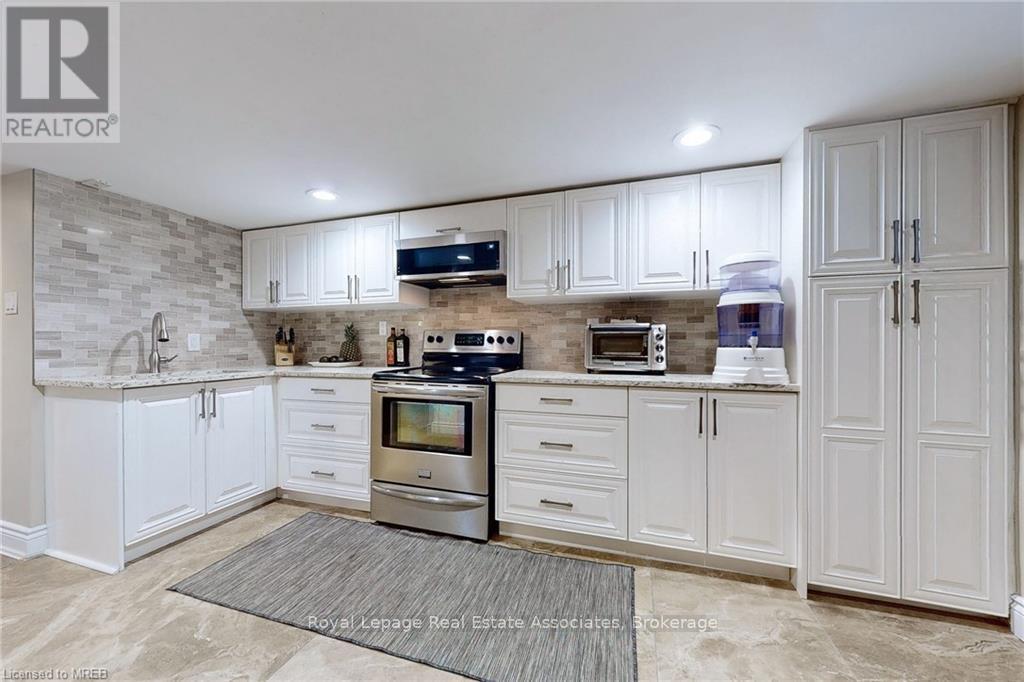 A kitchen with white cabinets and a stone backsplash.