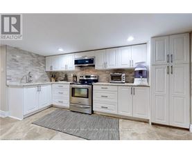 A kitchen with white cabinets and a stone backsplash.