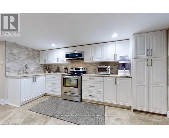 A kitchen with white cabinets and a stone backsplash.