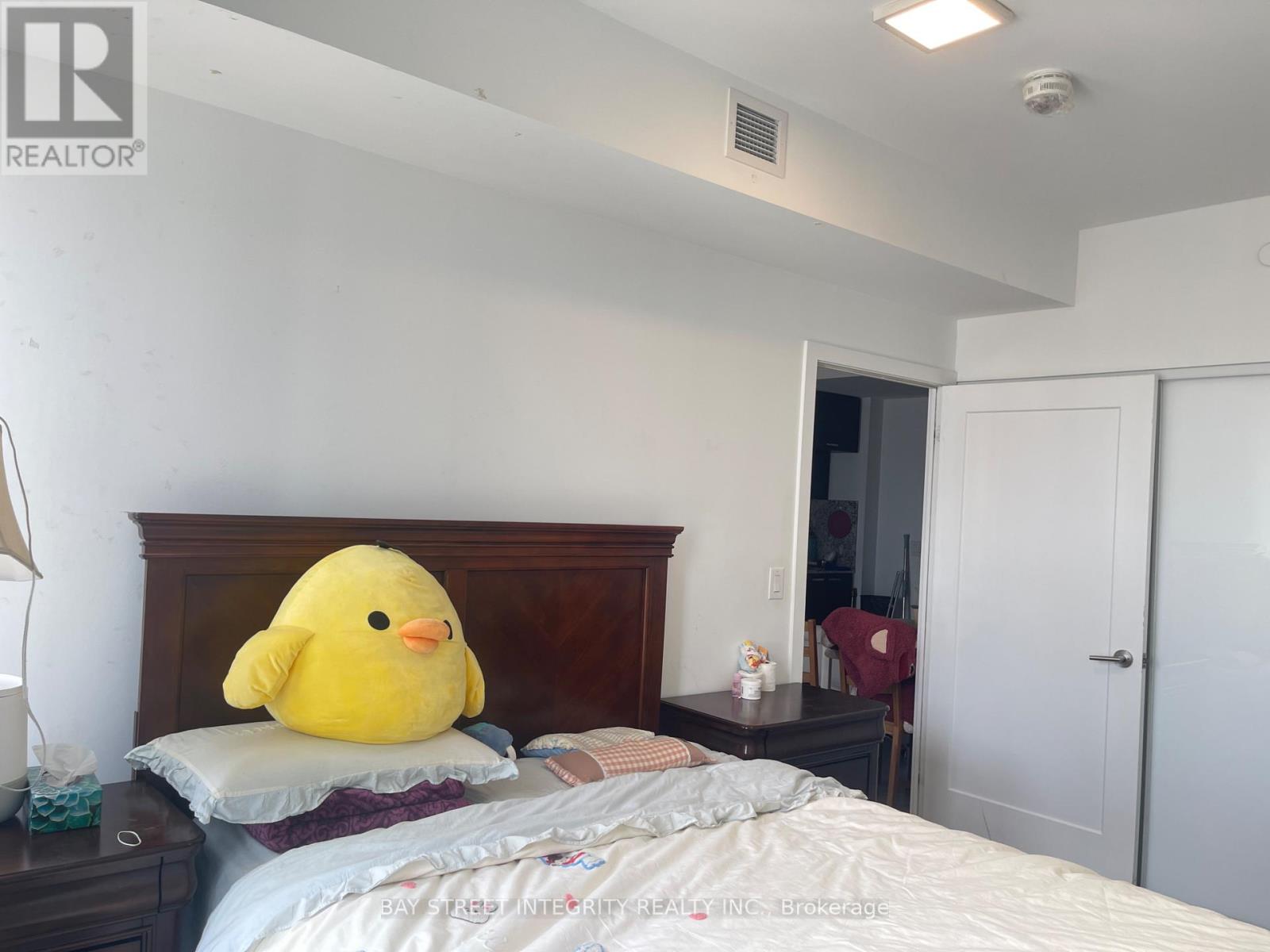 A bedroom with a large yellow duck pillow on the bed.