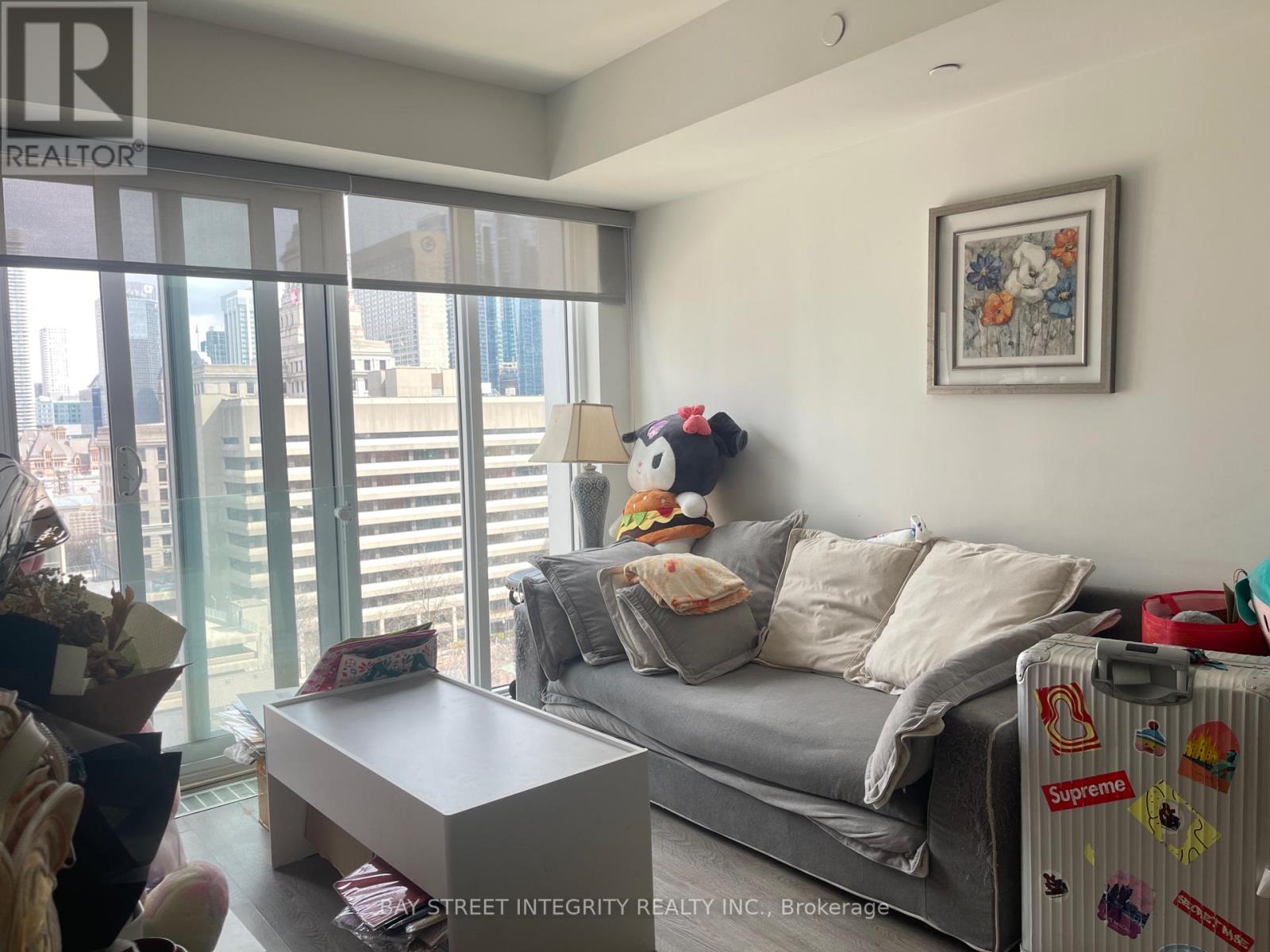 A living room with a grey couch and a painting on the wall.