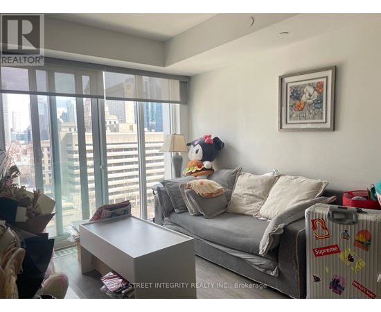 A living room with a grey couch and a painting on the wall.