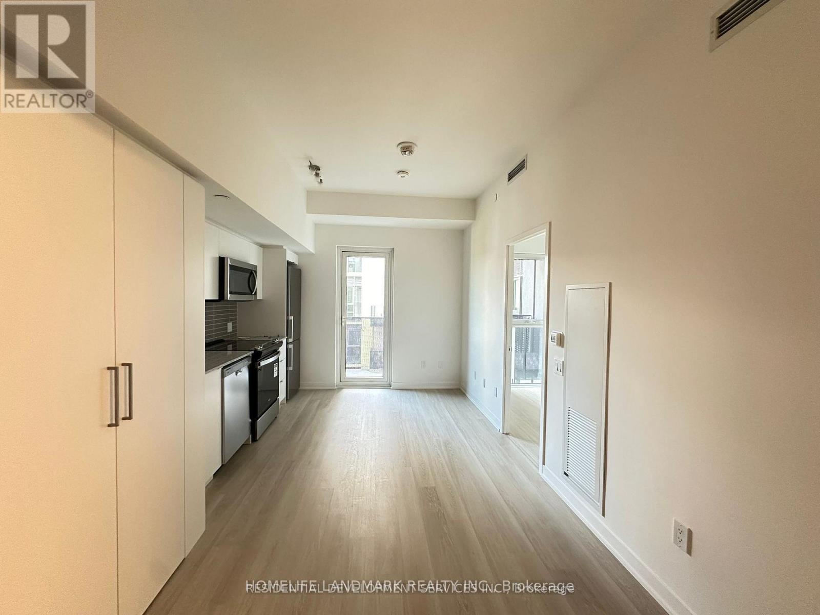 A spacious, empty apartment with a kitchen and a living area.