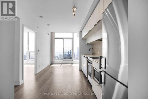 A modern kitchen with stainless steel appliances and wooden floors.
