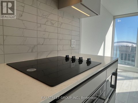 A modern kitchen with a black stove top and a marble backsplash.
